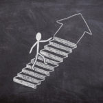 Chalkboard image of a stickman going up following an arrow.